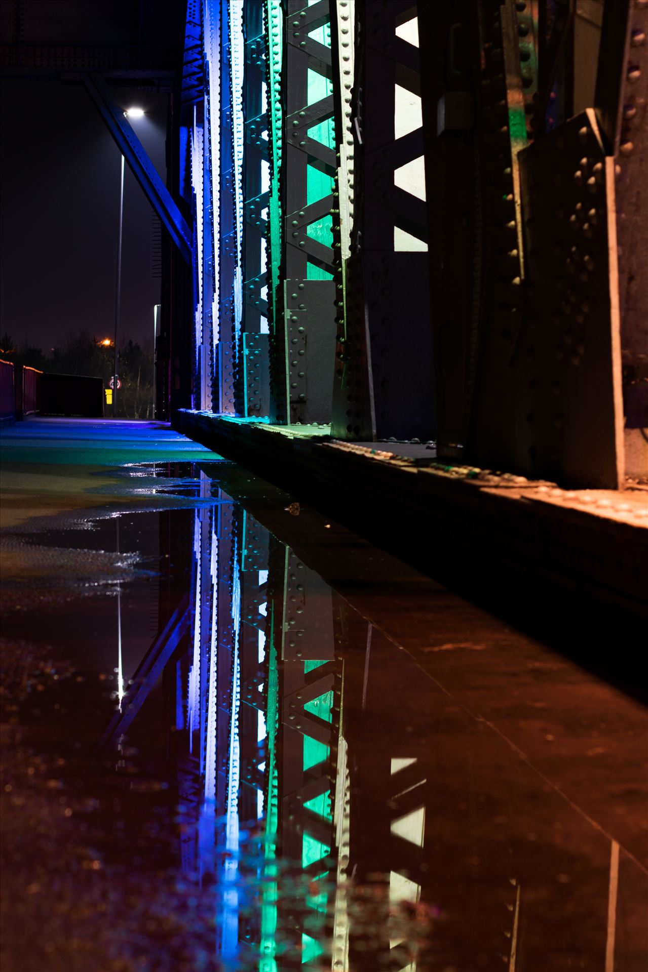Newport Bridge Rainbow Lights Puddle Refrlection - A photo of the lights on Newport Bridge and a puddle reflection. by AJ Stoves Photography
